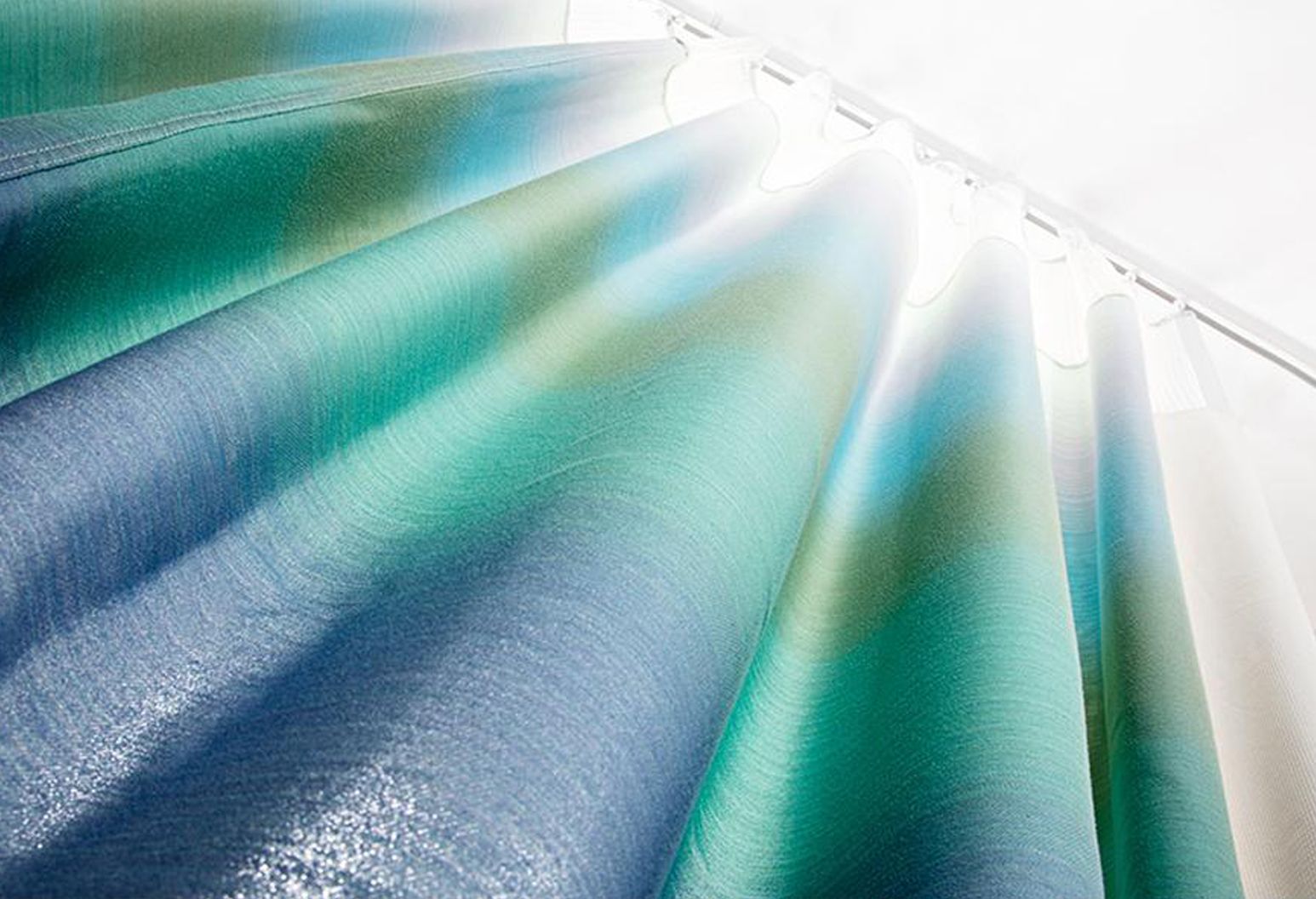 Image of a blue green hospital curtain. Viewer is looking up at the curtain and a light is shining down from the top.